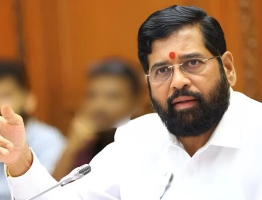Maharashtra Deputy Chief Minister Eknath Shinde, wearing a white shirt and glasses, speaks and gestures during an official meeting.